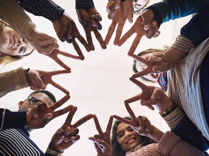 People in a circle holding their fingers out - fingers touching each other