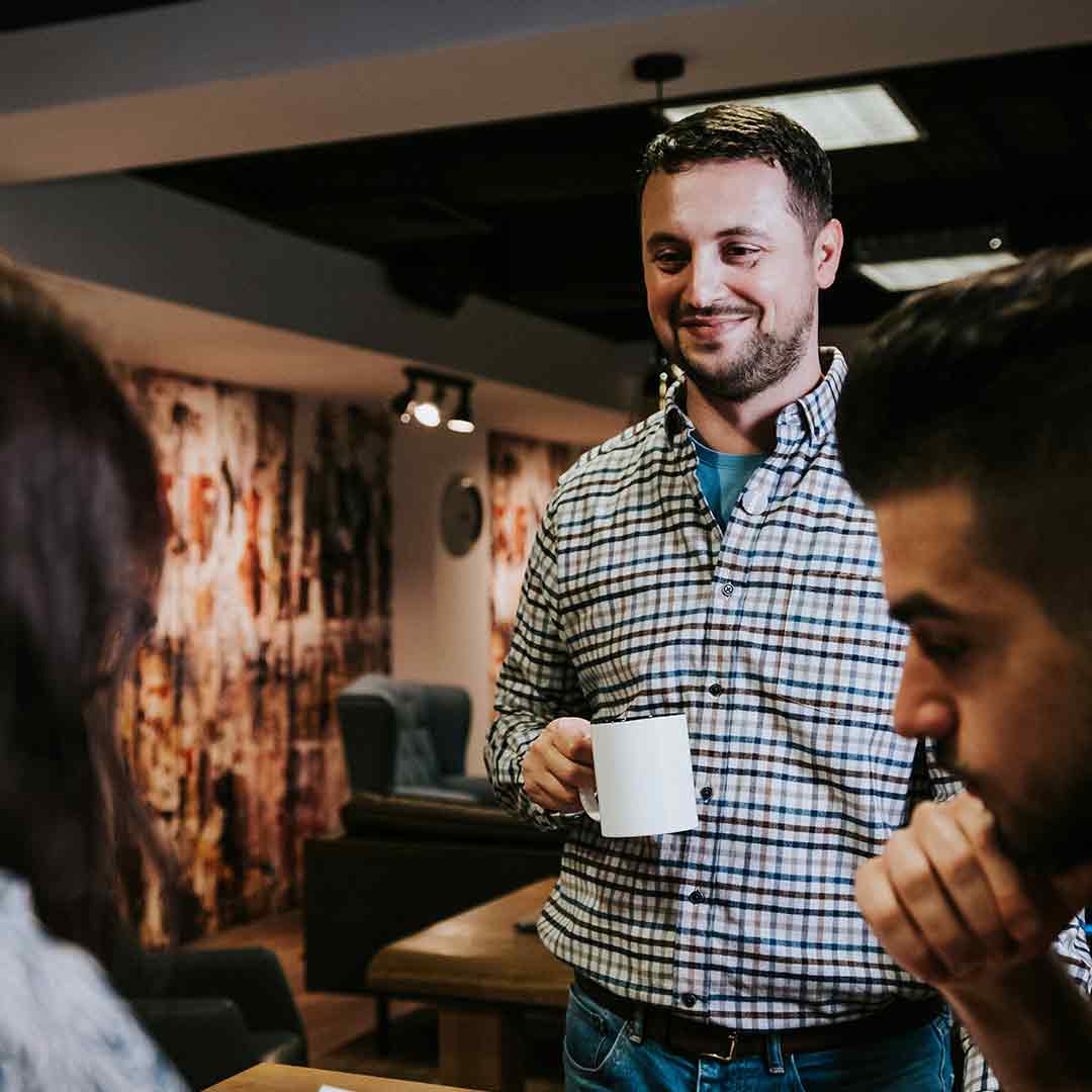 Three staff having coffee at work in conversation